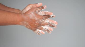 young man washing hands with soap warm water against gray background video