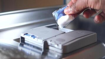 The person is using a soap dispenser for the dishwasher with their hand video