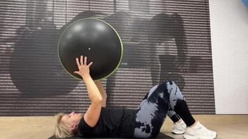 person är engagerad i kondition övning med stor, grönt trimmad svart övning boll. video