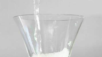 visa upp de framställning av en uppfriskande cocktail med stänga upp skott av ett tömma Martini glas varelse fylld med vatten och bubblor, resulterande i en utsökt vit flytande dryck på en tabell video