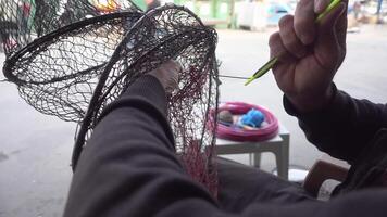 fiskare reparationer fisk fångst korg netto med netto reparera nål antal fot. video