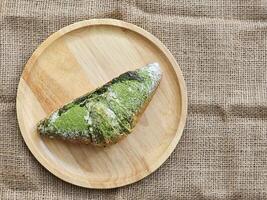 Green Tea Matcha Croissants stuffed with red bean paste on wooden plate. Top view photo