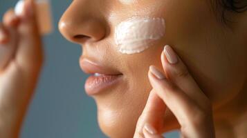 Woman applying sunscreen on her cheek in focus. skin care concept image. photo