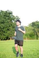 Young man with green t-shirt exercising and with gesture of suffering in park photo