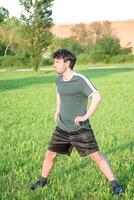 Young man with green t-shirt exercising and stretching in park photo
