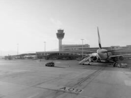 afines, Grecia - 20 agosto 2023. avión soportes con un escalera en frente de el aeropuerto edificio. espalda vista. negro y blanco foto
