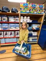Herceg-Novi, Montenegro - 17 august 2023. Little girl with a basket of books stands in a bookstore photo