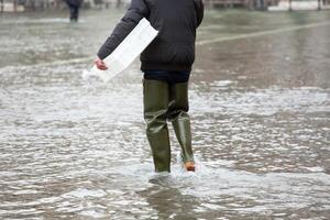 Close Up of legs with boots due to the high water in Venice. photo
