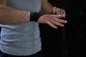 Anonymous kickboxer wrapping bandage on hand in gym photo