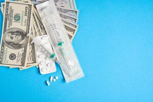 pills empty blisters for drugs individual syringe and money lie on a blue background photo