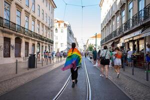 Gay person with rainbow flag walking on streets of Lisbon photo