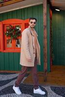 Handsome man in trendy outfit walking near Christmas house photo