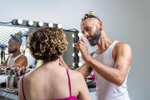 Gay man applying makeup on woman in studio photo