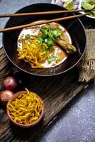 A female chef garnishing her Khao Soi Kai with a lime slide, Khao Soi Kai or Thai noodles curry with egg noodles and chicken drumstick. photo