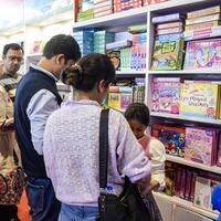 Delhi, India, February 17 2024 - Various age group people reading variety of Books on shelf inside a book-stall at Delhi International Book Fair, Books in Annual Book Fair at Bharat Mandapam complex photo