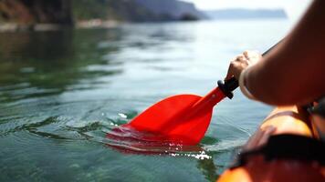 Kayak paddle sea vacation. Person paddles with orange paddle oar on kayak in sea. Leisure active lifestyle recreation activity rest tourism travel video