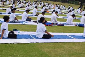 nuevo Delhi, India, junio 21, 2023 - grupo yoga ejercicio sesión para personas a yamuna Deportes complejo en Delhi en internacional yoga día, grande grupo de adultos asistiendo yoga clase en Grillo estadio foto