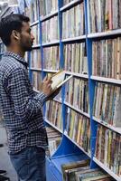 Delhi, India, February 17 2024 - Various age group people reading variety of Books on shelf inside a book-stall at Delhi International Book Fair, Books in Annual Book Fair at Bharat Mandapam complex photo