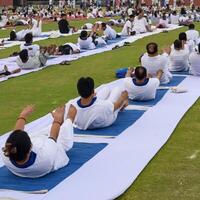 New Delhi, India, June 21, 2023 - Group Yoga exercise session for people at Yamuna Sports Complex in Delhi on International Yoga Day, Big group of adults attending yoga class in cricket stadium photo