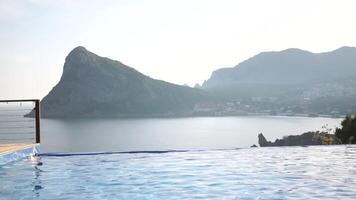 A pool with a beautiful view of the ocean. The water is calm and clear. The pool is surrounded by a wooden deck. video