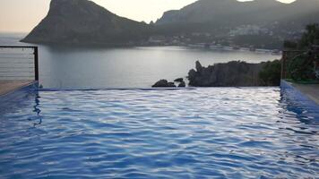 A pool with a beautiful view of the ocean. The water is calm and clear. The pool is surrounded by a wooden deck. video