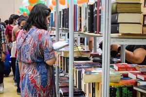 Delhi, India, September 09 2023 - Various age group people reading variety of Books on shelf inside a book-stall at Delhi International Book Fair, Selection of books on display in Annual Book Fair photo