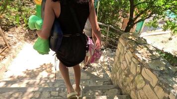 een vrouw is wandelen naar beneden een reeks van trap met een groen handdoek in haar hand. ze is vervelend een zwart rok en een zwart tank top. video
