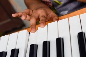 Asian cute girl playing the synthesizer or piano. Cute little kid learning how to play piano. Child's hands on the keyboard indoor. photo