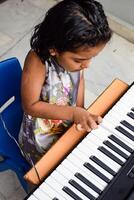 Asian cute girl playing the synthesizer or piano. Cute little kid learning how to play piano. Child's hands on the keyboard indoor. photo