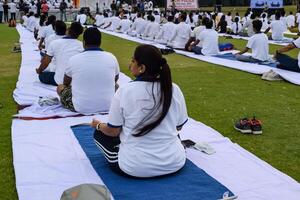 nuevo Delhi, India, junio 21, 2023 - grupo yoga ejercicio sesión para personas a yamuna Deportes complejo en Delhi en internacional yoga día, grande grupo de adultos asistiendo yoga clase en Grillo estadio foto