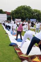 nuevo Delhi, India, junio 21, 2023 - grupo yoga ejercicio sesión para personas a yamuna Deportes complejo en Delhi en internacional yoga día, grande grupo de adultos asistiendo yoga clase en Grillo estadio foto