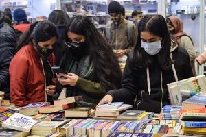 Delhi, India, February 17 2024 - Various age group people reading variety of Books on shelf inside a book-stall at Delhi International Book Fair, Books in Annual Book Fair at Bharat Mandapam complex photo