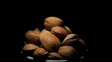 Bowl with almonds nuts in rotation on black background video