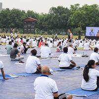 New Delhi, India, June 21, 2023 - Group Yoga exercise session for people at Yamuna Sports Complex in Delhi on International Yoga Day, Big group of adults attending yoga class in cricket stadium photo