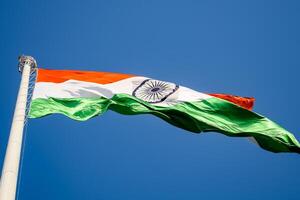 India flag flying high at Connaught Place with pride in blue sky, India flag fluttering, Indian Flag on Independence Day and Republic Day of India, tilt up shot, Waving Indian flag, Har Ghar Tiranga photo