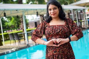 A pregnant Indian lady poses for outdoor pregnancy shoot and hands on belly, Indian pregnant woman puts her hand on her stomach with a maternity dress at society park, Pregnant outside maternity shoot photo