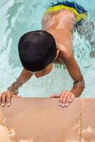 contento indio chico nadando en un piscina, niño vistiendo nadando disfraz a lo largo con aire tubo durante caliente verano vacaciones, niños chico en grande nadando piscina. foto