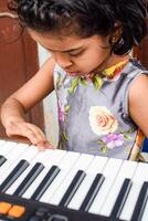 Asian cute girl playing the synthesizer or piano. Cute little kid learning how to play piano. Child's hands on the keyboard indoor. photo