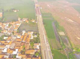 Foggy view of the railway line. Aerial view of train track and station in Rancaekek, Bandung - Indonesia. Natural conditions. Above. Public transportation. Shot in drone flying 100 meters photo