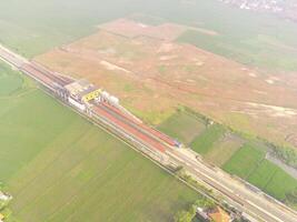 Foggy view of the railway line. Aerial view of train track and station in Rancaekek, Bandung - Indonesia. Natural conditions. Above. Public transportation. Shot in drone flying 100 meters photo