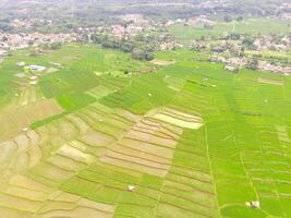 View of local Farm at the top of the hill. Aerial view of rice fields and plantations in Cicalengka, Bandung - Indonesia. Above. Agriculture Industry. Shot in drone flying 100 meters photo