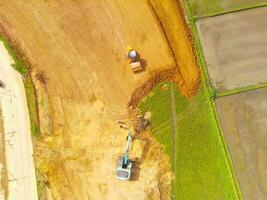 Heavy equipment vehicles are leveling the ground. Aerial drone view of Housing development on the edge of the city. View from above, Housing Industry. Above. Social issues. Shot from drone flying photo