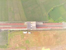 Foggy view of the Railway station. Aerial view of train track and station in Rancaekek, Bandung - Indonesia. Natural conditions. Above. Public transportation. Shot in drone flying 100 meters photo