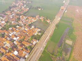 brumoso ver de el ferrocarril línea. aéreo ver de tren pista y estación en rancaekek, Bandung - Indonesia. natural condiciones. arriba. público transporte. Disparo en zumbido volador 100 metros foto