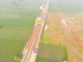 Foggy view of the railway line. Aerial view of train track and station in Rancaekek, Bandung - Indonesia. Natural conditions. Above. Public transportation. Shot in drone flying 100 meters photo