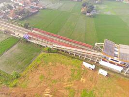 Foggy view of the Railway station. Aerial view of train track and station in Rancaekek, Bandung - Indonesia. Natural conditions. Above. Public transportation. Shot in drone flying 100 meters photo