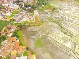 aéreo Disparo de el pueblo rodeado por grande arroz campos. aéreo ver de asentamientos en el arroz campos en rancaekek, Bandung - Indonesia. arriba. agricultura industria. Disparo desde zumbido volador foto