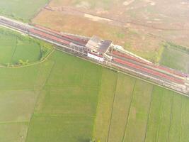 Foggy view of the railway line. Aerial view of train track and station in Rancaekek, Bandung - Indonesia. Natural conditions. Above. Public transportation. Shot in drone flying 100 meters photo