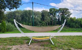 A hammock made of natural fabric, suspended from ropes in the garden on a metal frame photo