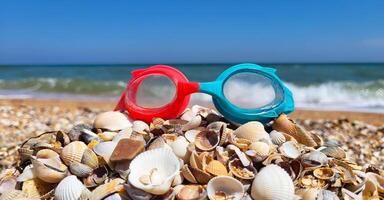 There are swimming goggles on the shells against the background of blue sea waves. Banner with the concept of summer, diving, travel, vacation, holiday card photo